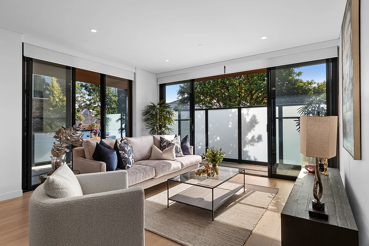 Bright living room in an independent living apartment at Hester Canterbury, offering retirement living in Melbourne with a sofa and sliding doors to a private balcony.